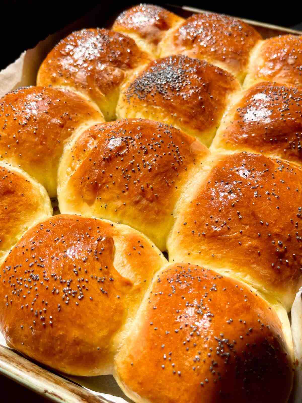 Freshly baked golden brown burger buns cooling in a pan