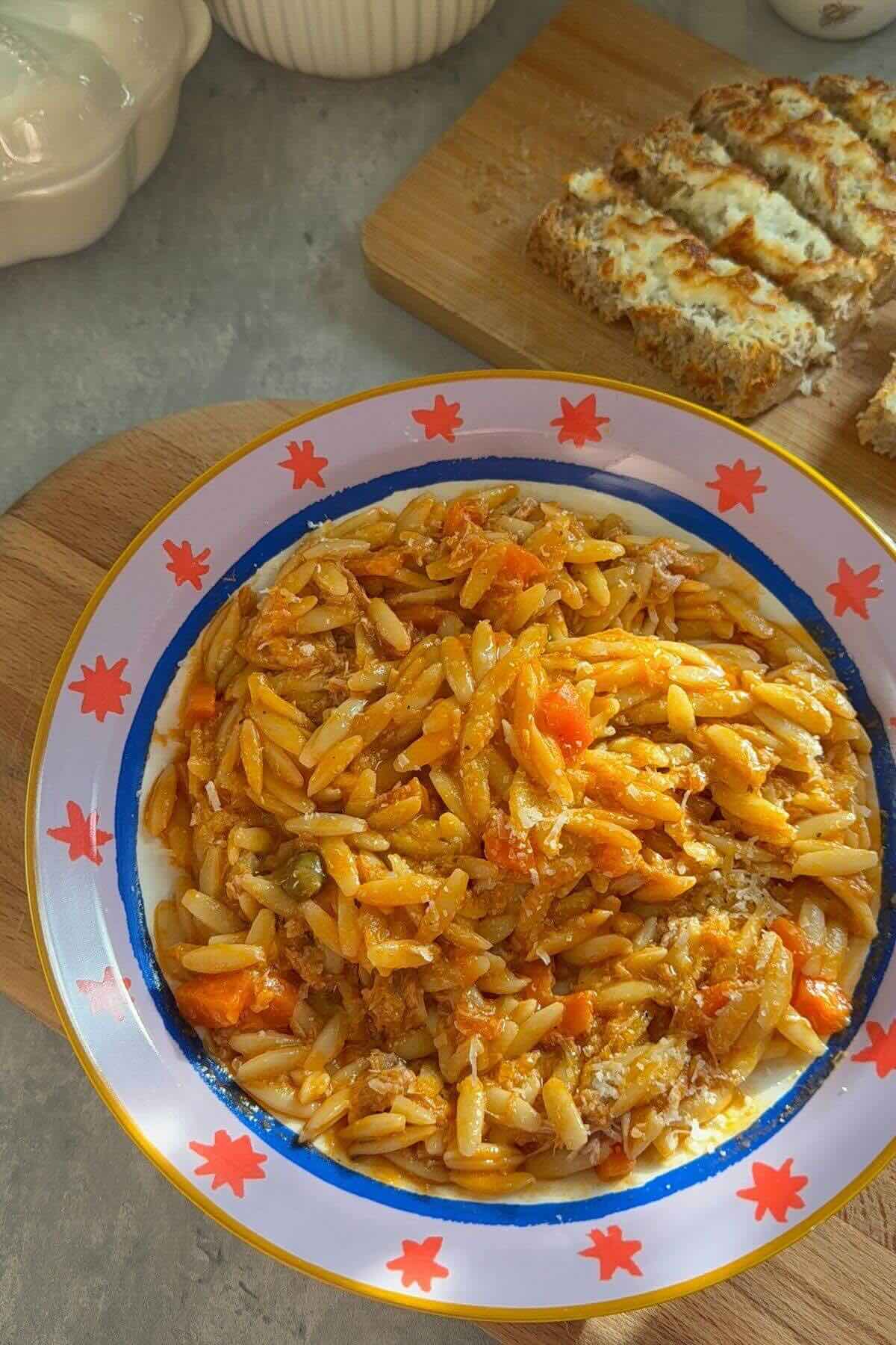 Creamy tomato orzo with canned tuna and parmesan on a plate.