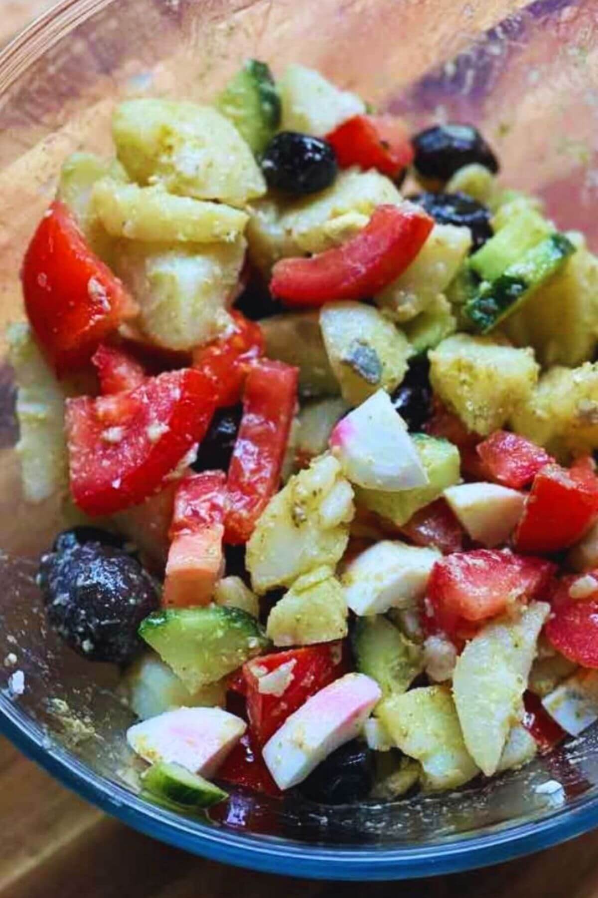 Fresh potato salad with boiled eggs, cucumber, tomato, and olives, a colorful and healthy Mediterranean-inspired dish.
