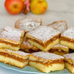 Delicious homemade apple cake with a golden crust, slices of fresh apples, and a dusting of powdered sugar on top.