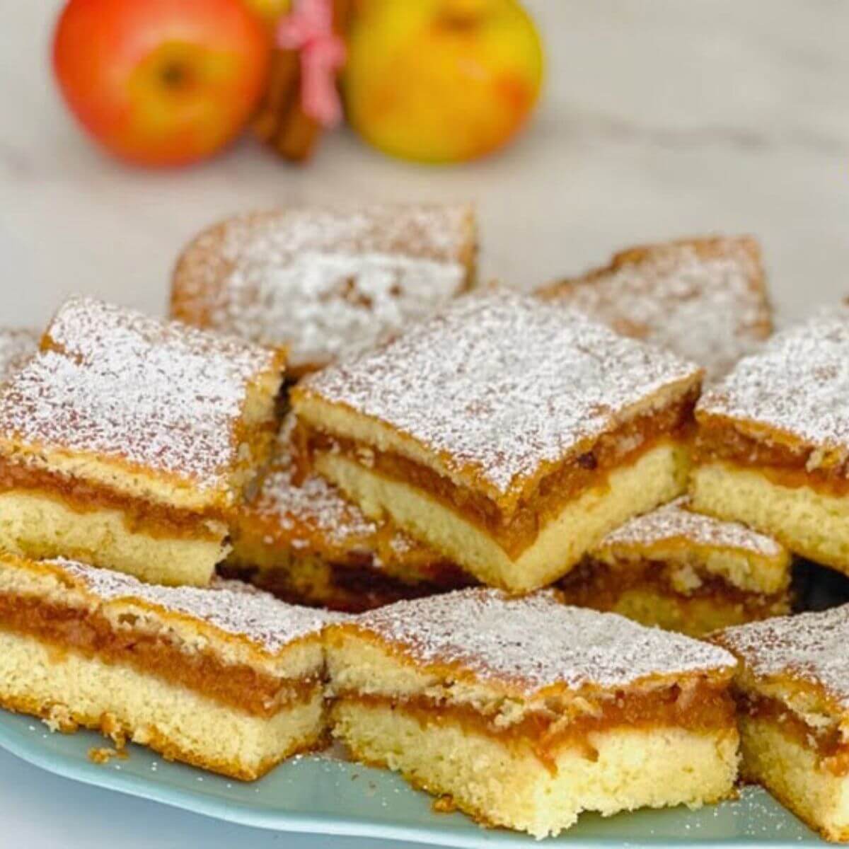 Delicious homemade apple cake with a golden crust, slices of fresh apples, and a dusting of powdered sugar on top.