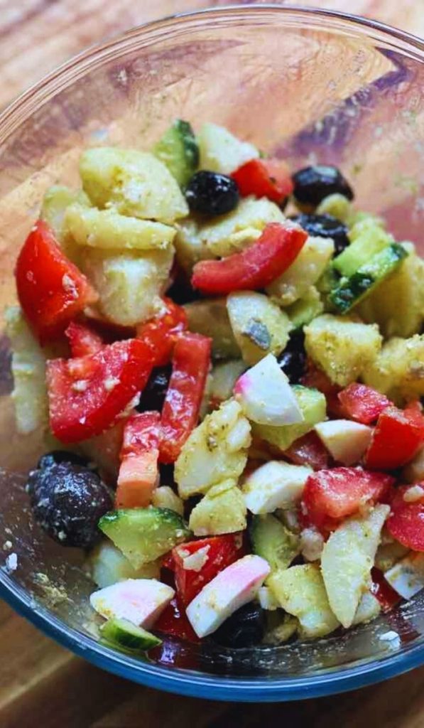 Fresh potato salad with boiled eggs, cucumber, tomato, and olives, a colorful and healthy Mediterranean-inspired dish.
