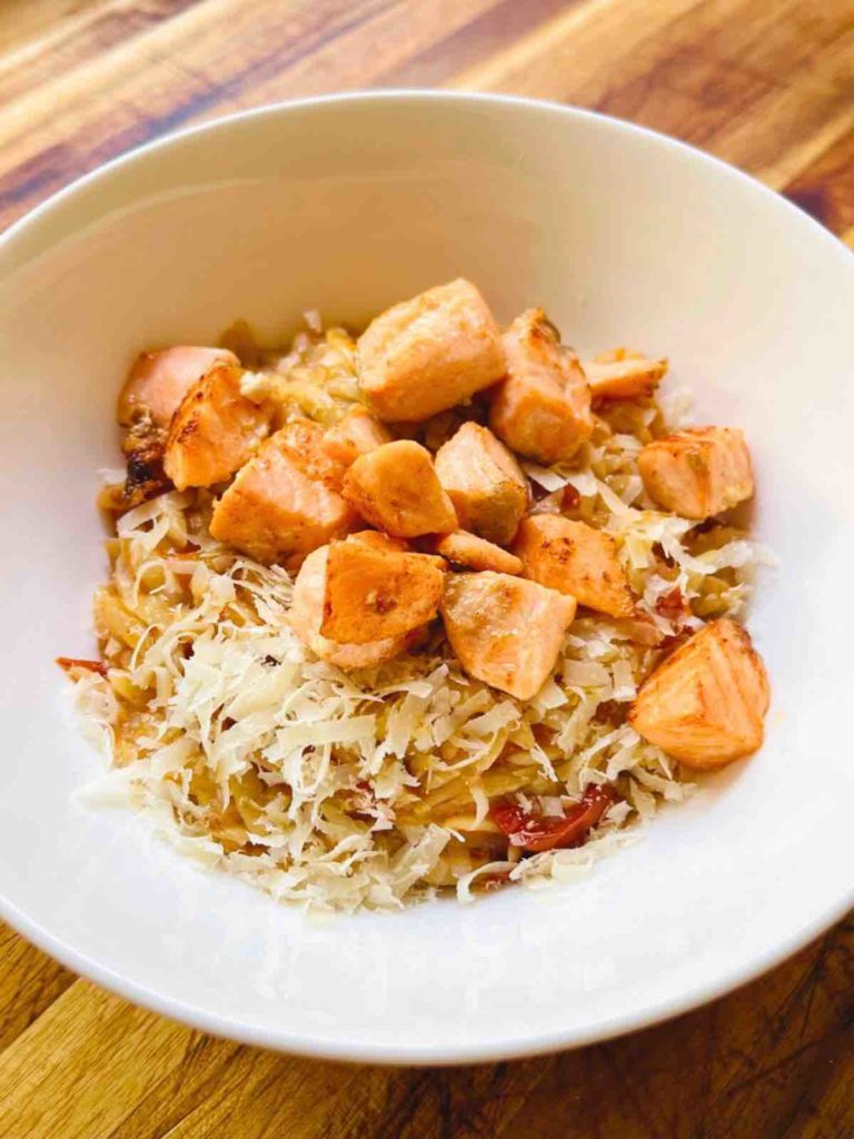 Tomato orzo with grilled salmon served in a bowl