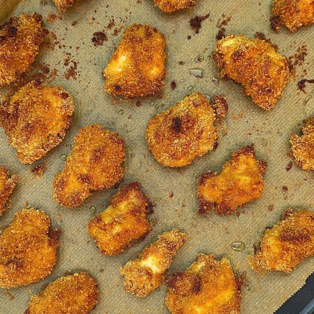 Golden baked chicken nuggets with crispy breadcrumb coating, arranged on a baking tray.