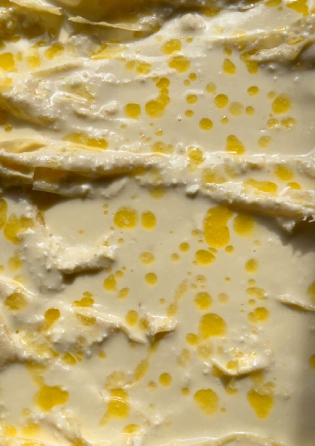 Layer of creamy cheese filling added to the crinkled phyllo sheets in a baking pan."