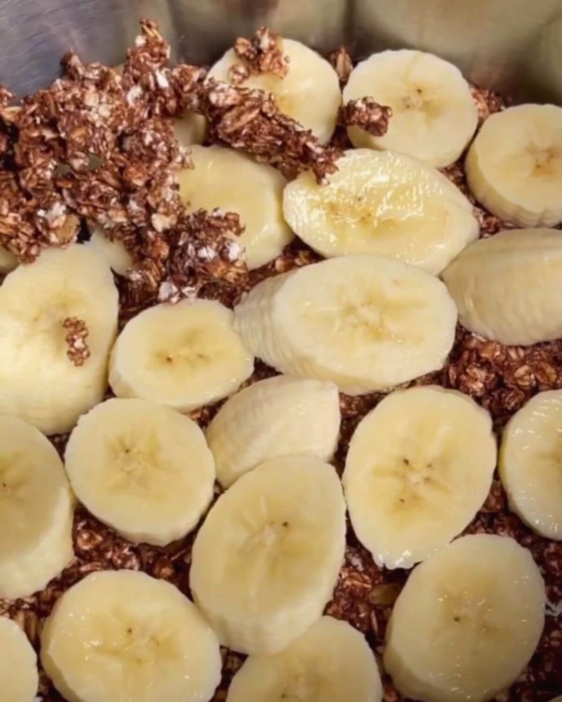 Layering the cake with sliced bananas and a chocolate-oat mixture.