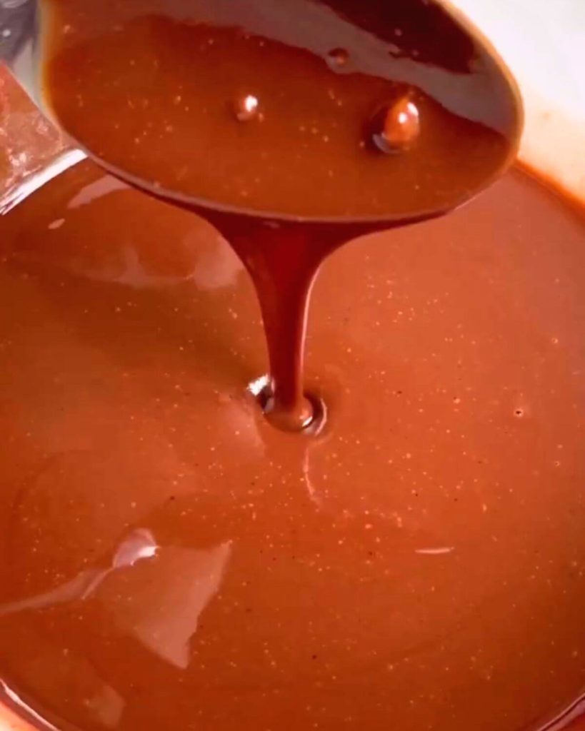 Ganache perfection - a spoon testing its glossy, dripping texture.