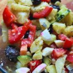 Fresh potato salad with boiled eggs, cucumber, tomato, and olives, a colorful and healthy Mediterranean-inspired dish.