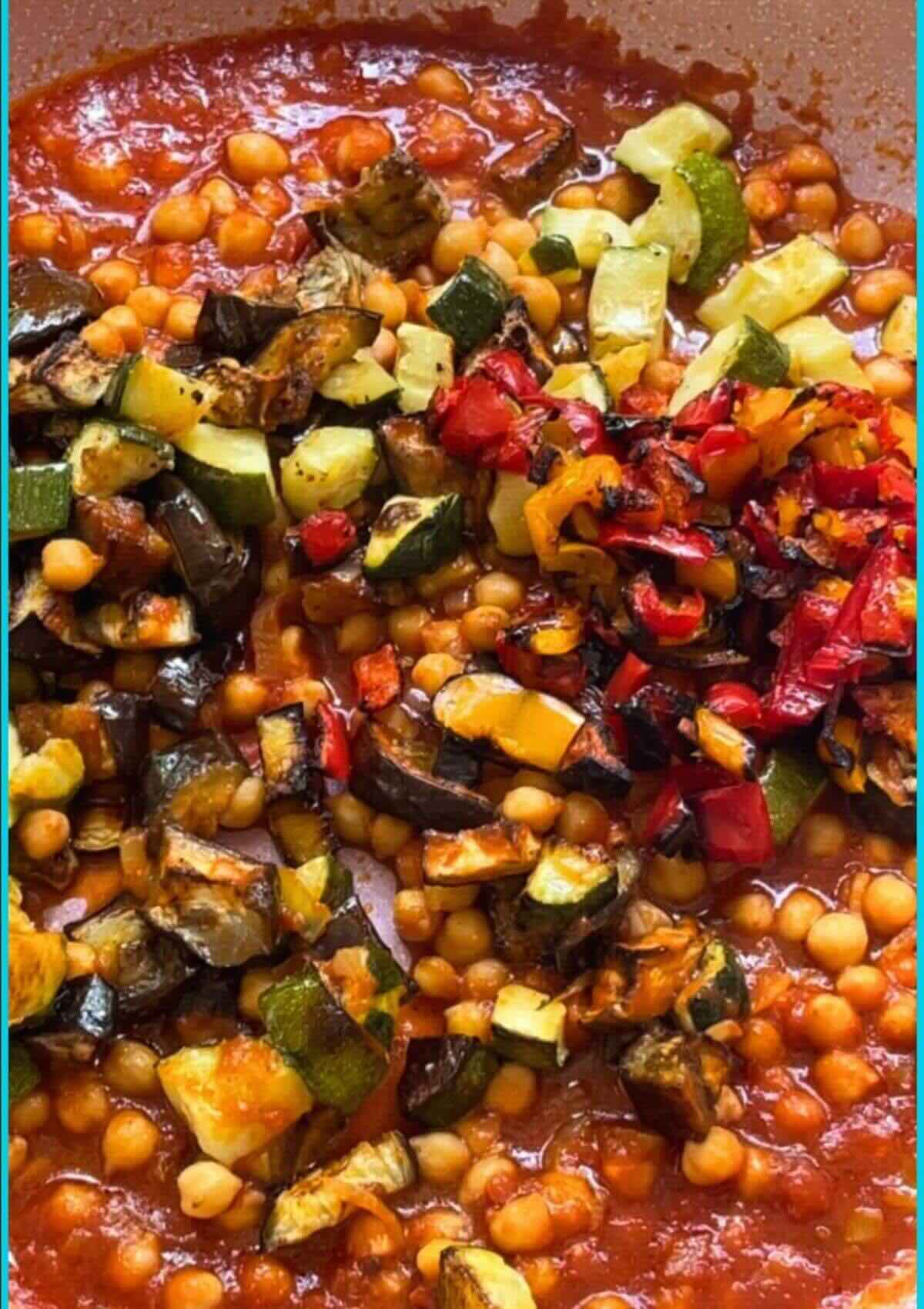 Pan with chopped onion, seasoned with salt, smoked paprika, and tomato sauce, with roasted vegetables added.