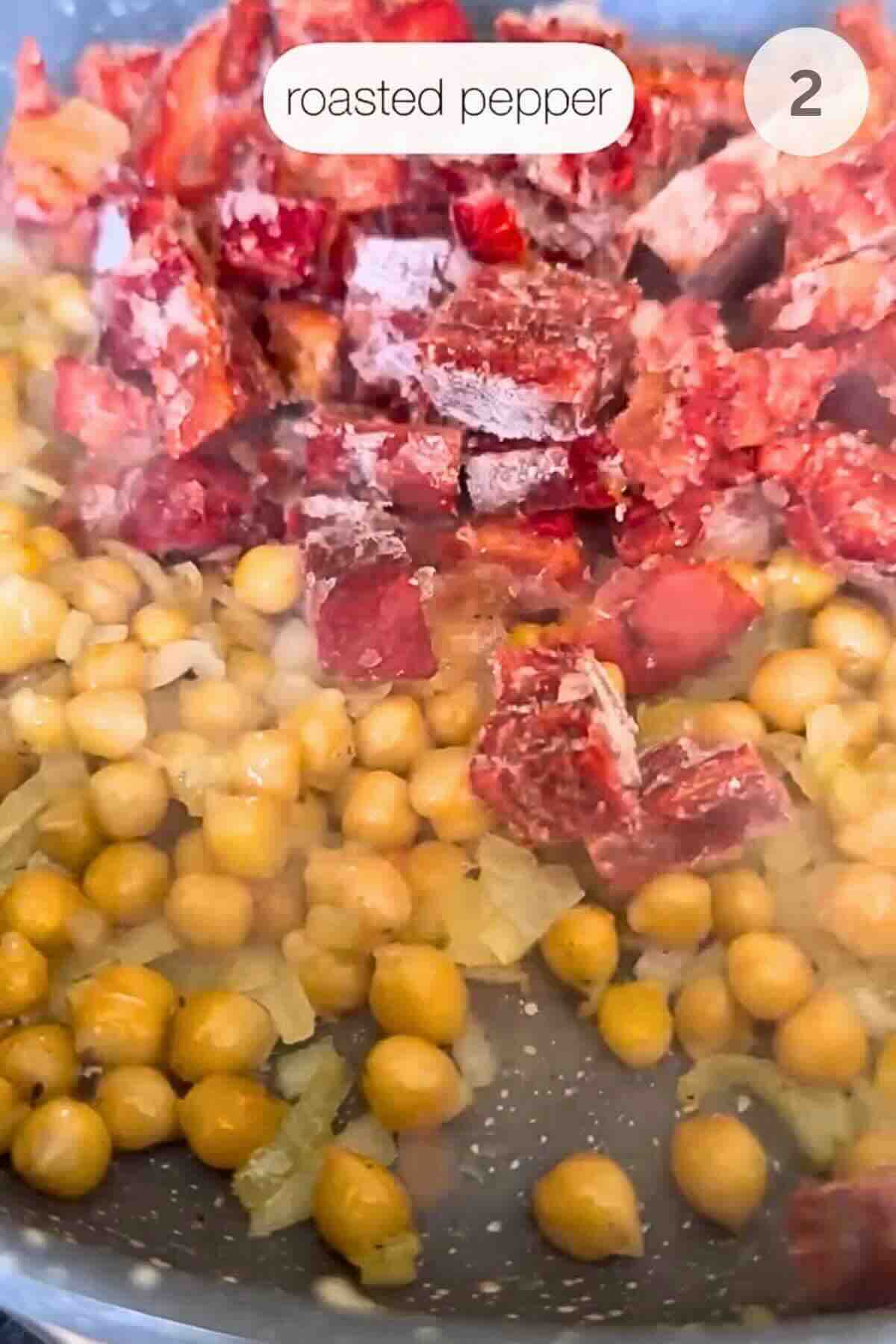Frozen charred, peeled red pepper being added to sautéed onion and chickpeas.