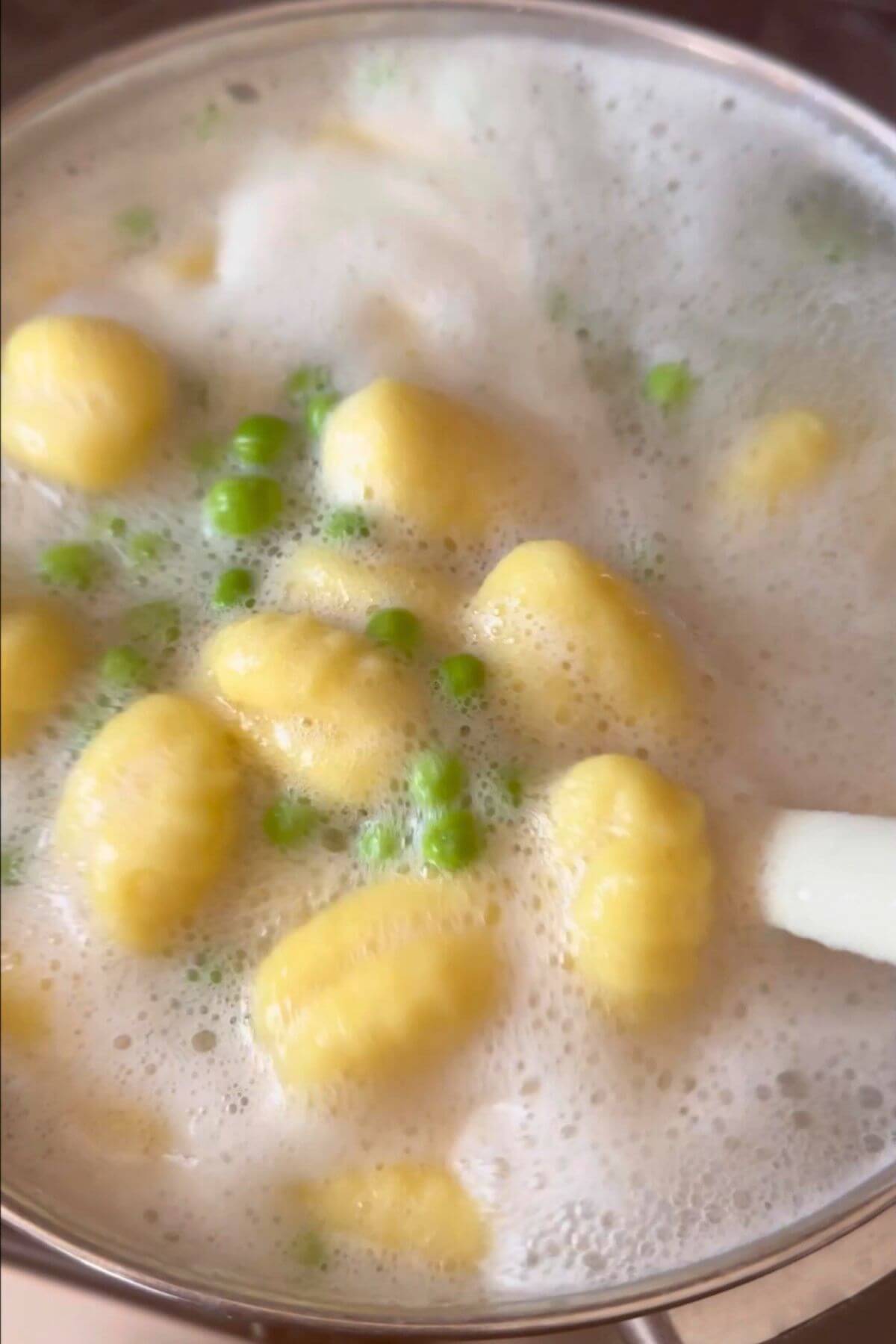 Gnocchi and peas boiling together in a pot, ready for a pesto dish