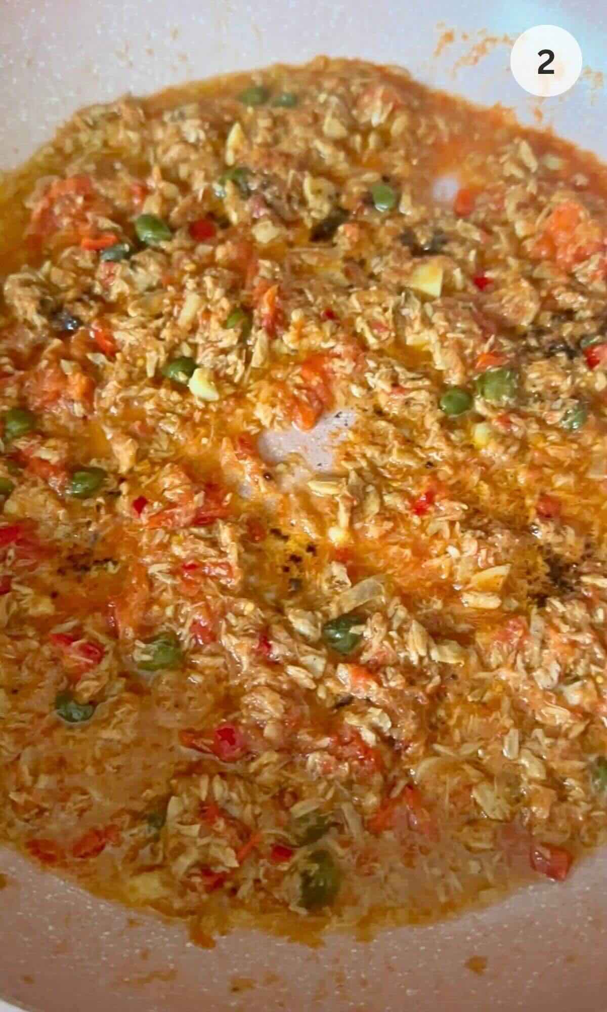 Pan with tuna in olive oil, garlic, chili, and capers, simmering in tomato sauce.