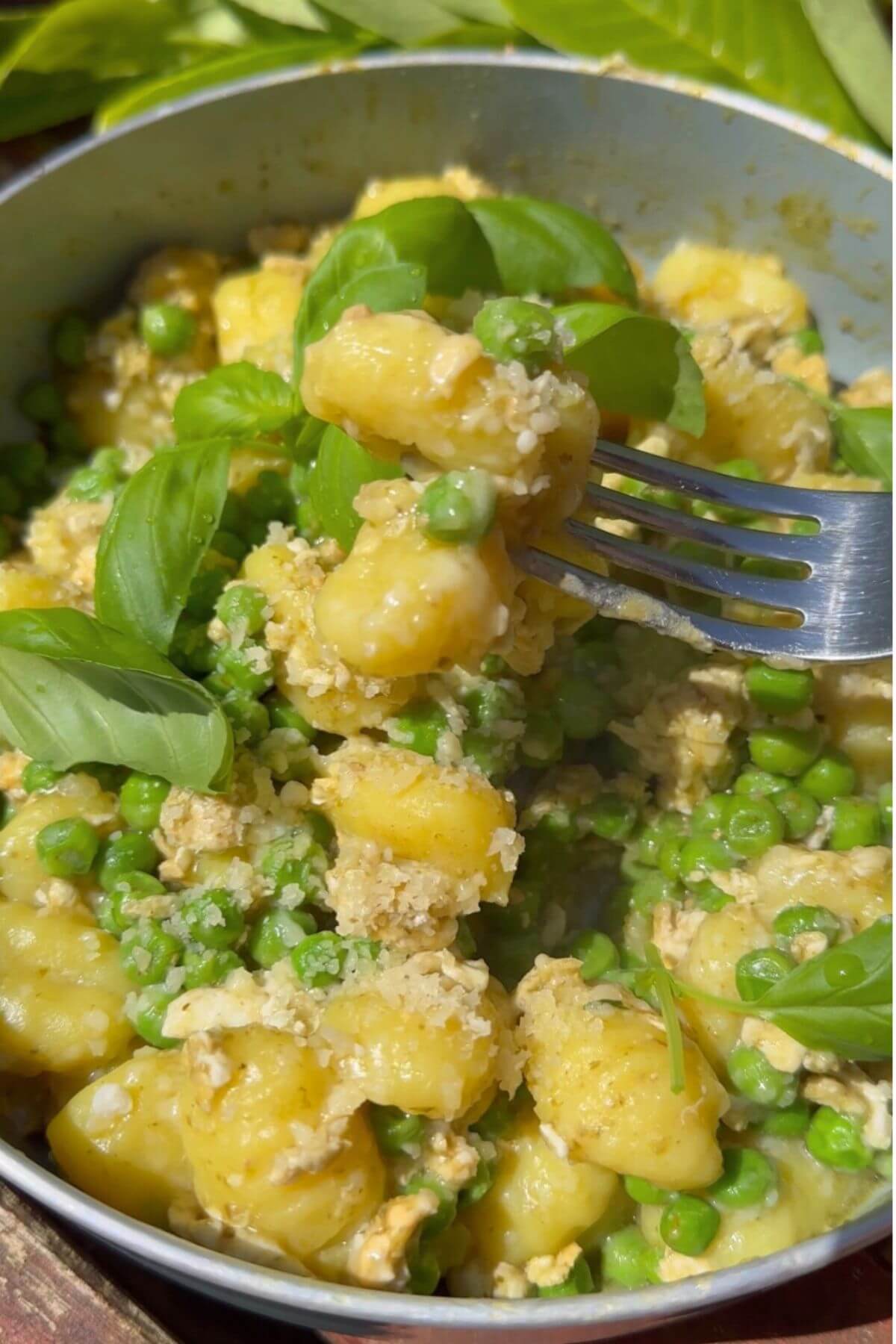 The dish is garnished with fresh basil leaves and extra Parmesan, a spoon lifting a bite.