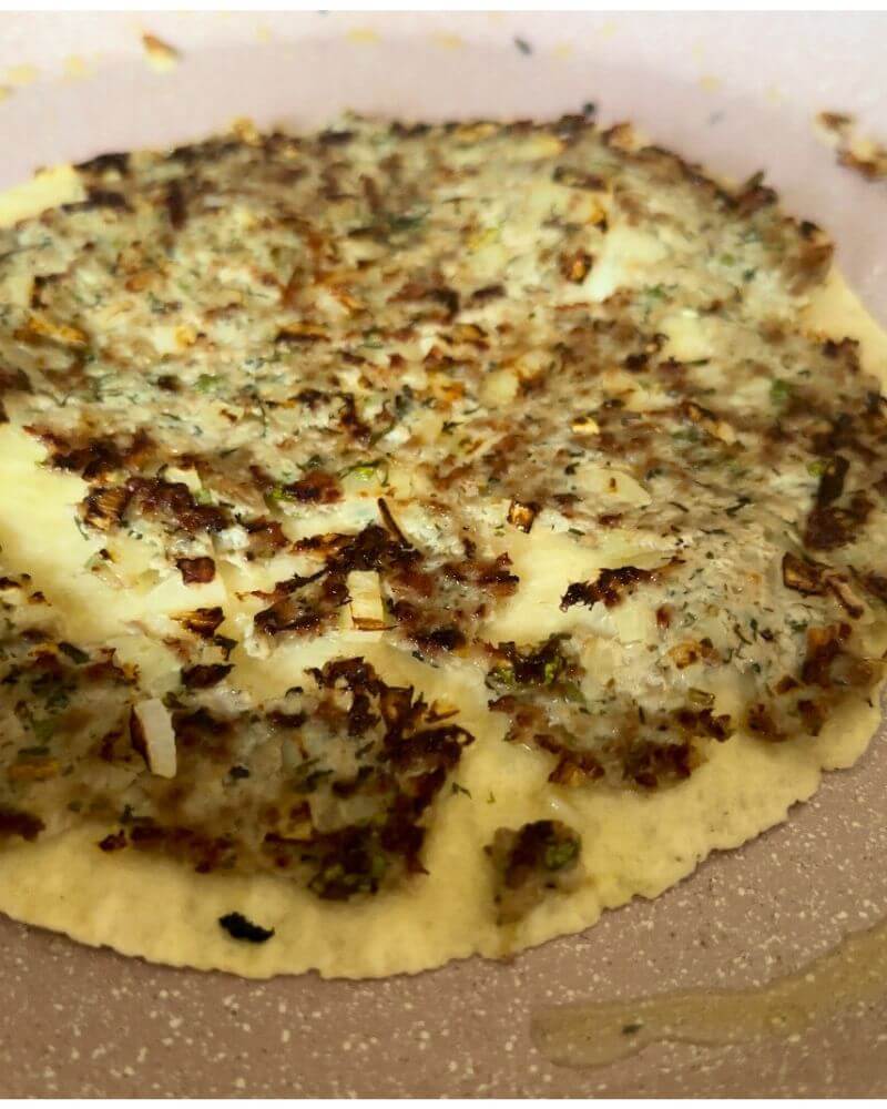 Fried kefta on tortilla cooking in a pan for Smashed Kefta Tacos.