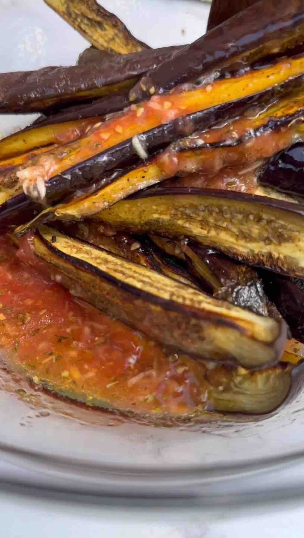 ossing cooked aubergines in a bowl with a freshly mixed tomato dressing.