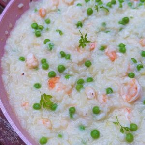 Delicious Prawn and Pea Risotto presented in a pan, with plump prawns and vibrant green peas, garnished with parsley leaves.