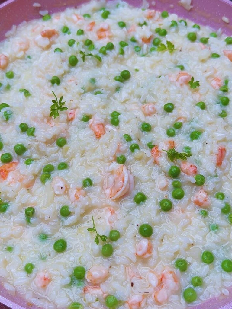 Delicious Prawn and Pea Risotto presented in a pan, with plump prawns and vibrant green peas, garnished with parsley leaves.