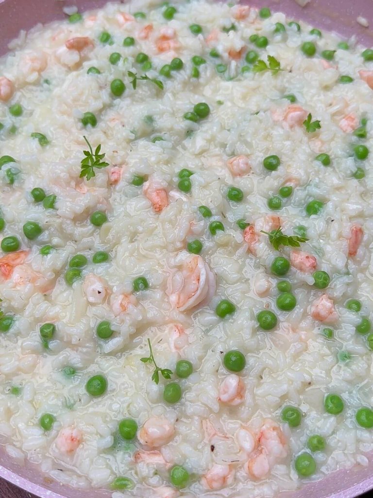 Delicious Prawn and Pea Risotto presented in a pan, with plump prawns and vibrant green peas, garnished with parsley leaves.