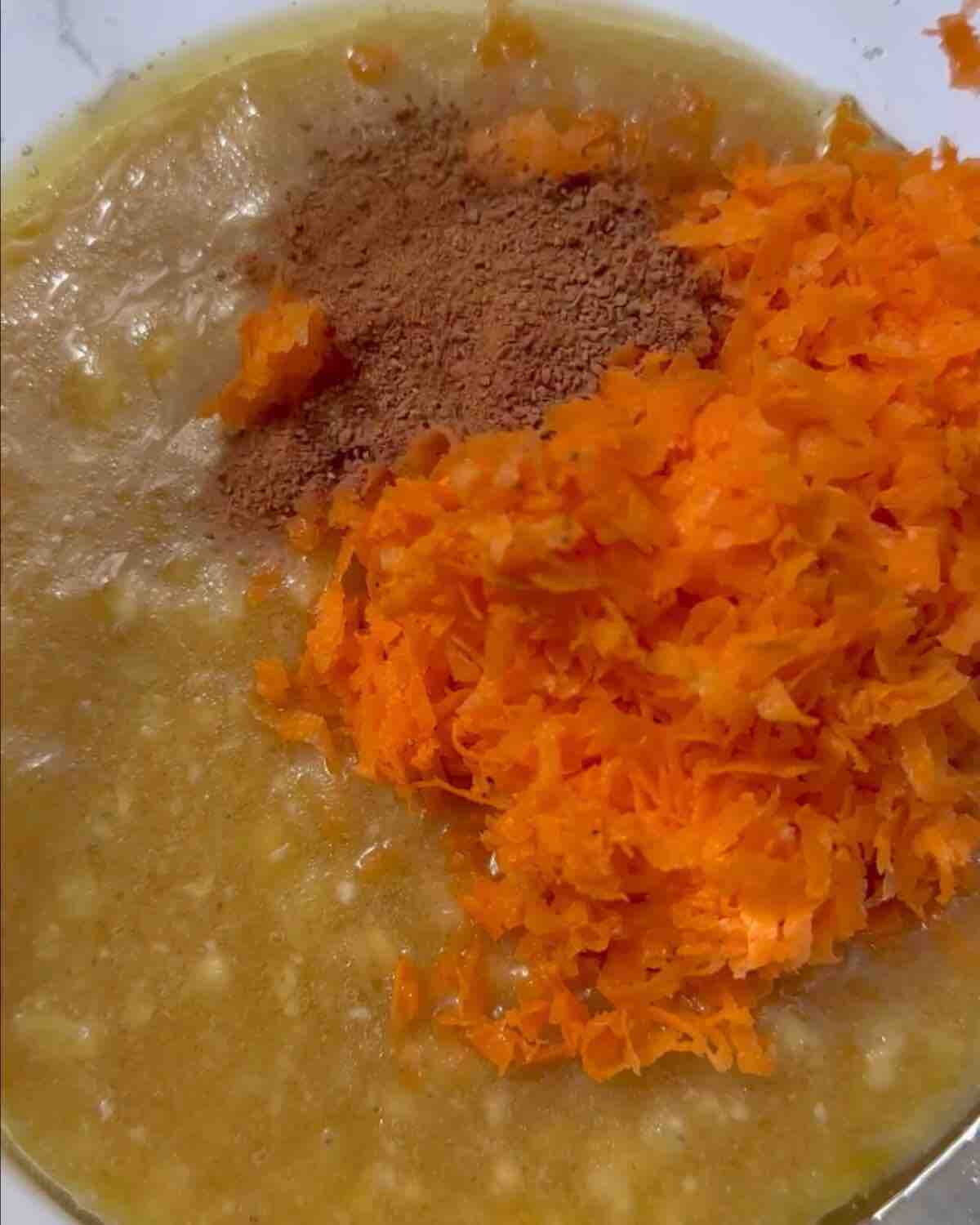 A bowl with mashed bananas, plant-based milk, and oil, ready to be mixed for baking.