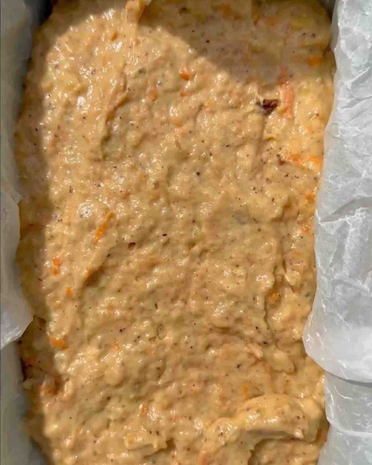 A parchment-lined loaf pan filled with batter, ready to go into the oven.