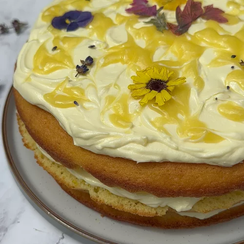 Three Layer Lemon Cake decorated with lemon cream cheese frosting, lemon curd swirls and edible flowers.