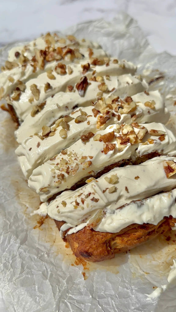 Sliced Vegan Carrot Cake Banana Bread topped with cream cheese frosting and chopped walnuts. 