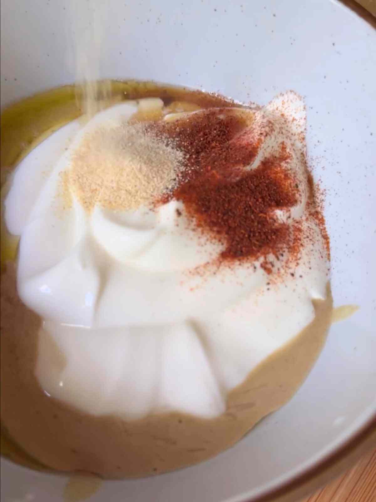 Creamy tahini sauce made with tahini paste, lemon juice, Greek yogurt (vegan version available), olive oil, maple syrup, minced garlic, chili powder, and salt.