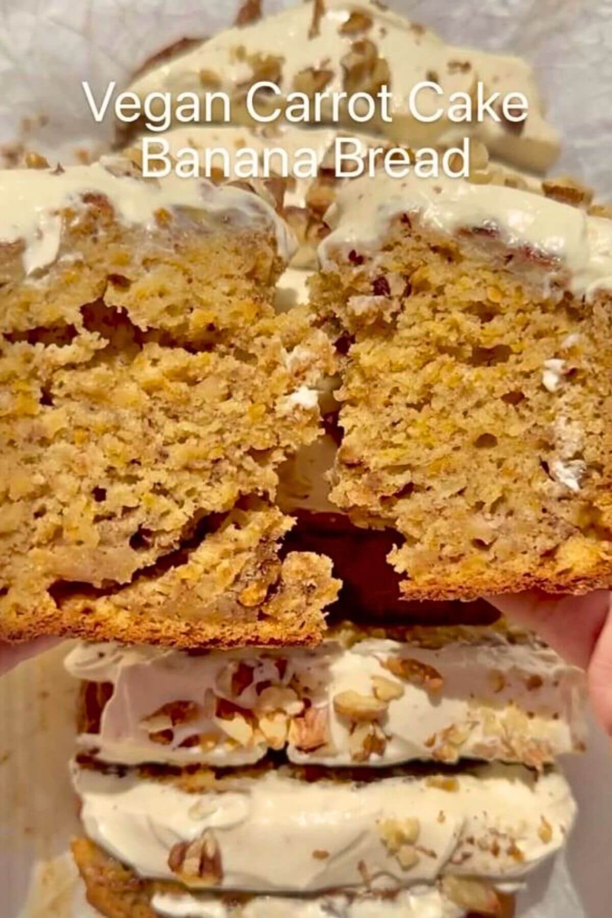 Vegan carrot cake banana bread topped with cream cheese frosting, walnuts, and a slice showing the inside.