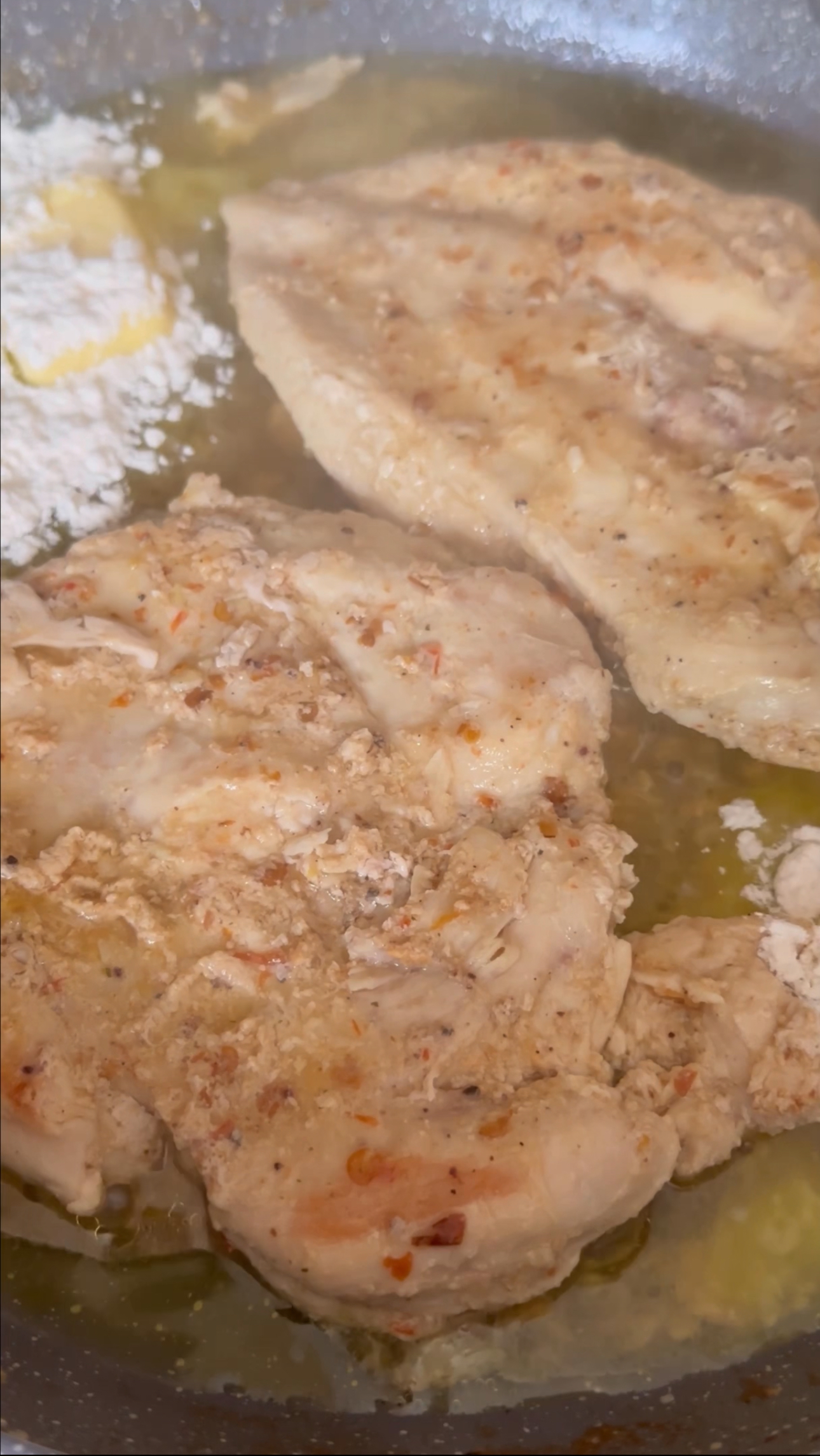 A photo showing two cooked pieces of chicken breast in a pan. 