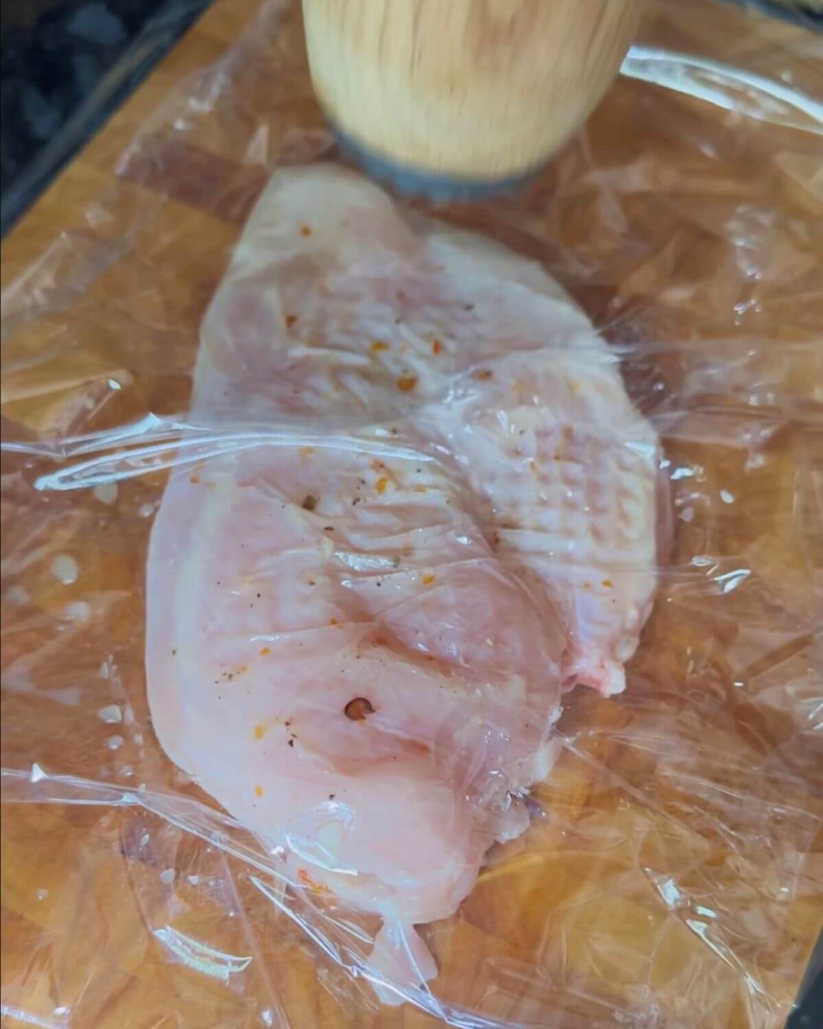 A photo showing a chicken breast wrapped in clingfilm ready to be tenderised.