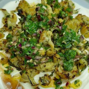 Roasted cauliflower florets topped with creamy Greek yogurt and drizzled with vibrant chimichurri sauce