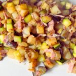 Plate of sizzling bacon, tender potatoes, and sautéed zucchini hash.