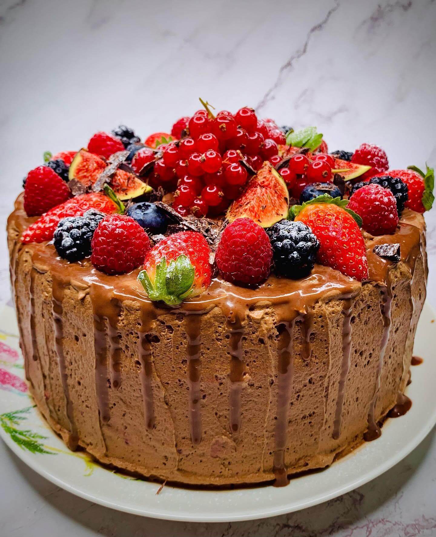 A chocolate cake topped with fresh berries and a rich chocolate drizzle.