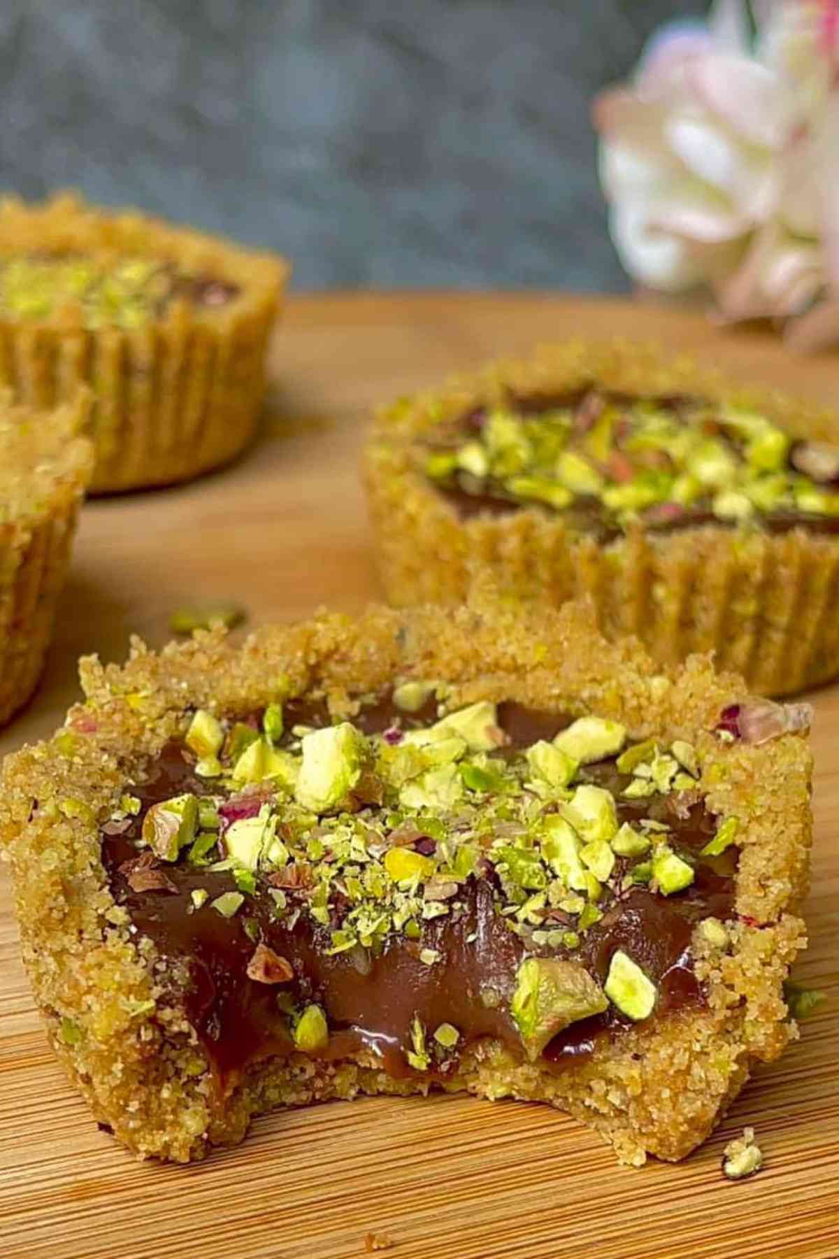 Chocolate Mini Tarts on a wooden board with one tart bitten to see the section. 