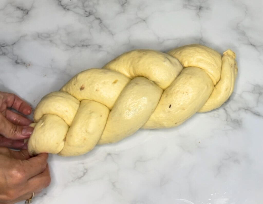 A picture of three walnut-filled rolls all braided together on a table, creating a walnut roll.
