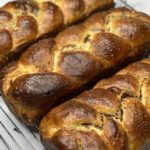 3 warm walnut rolls resting on a wire rack.