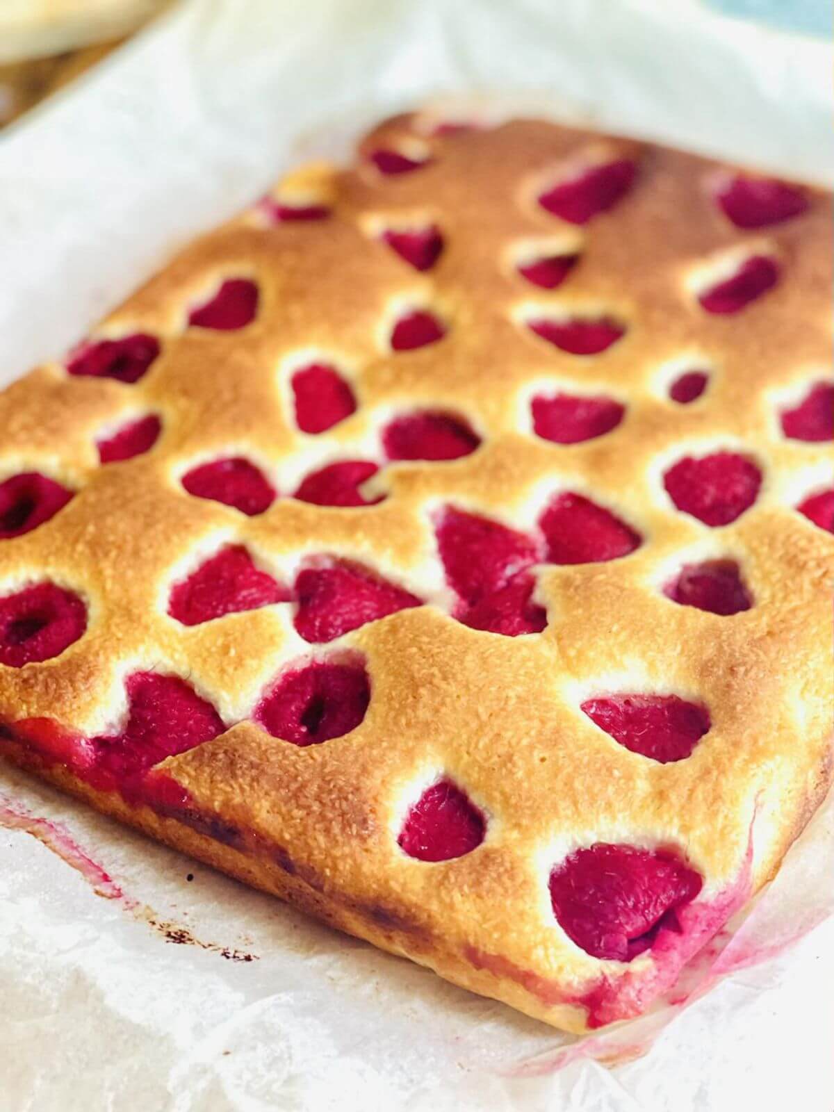 Uncut Raspberry Coconut Cake on  parchment paper. 