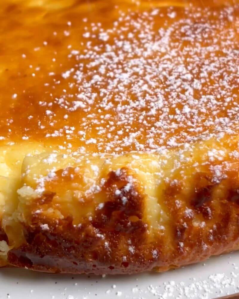 Golden-brown baked flourless yogurt cake, dusting powdered sugar on top for a sweet finish.