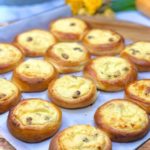 Freshly baked golden brown mini ricotta cakes cooling on a baking tray.