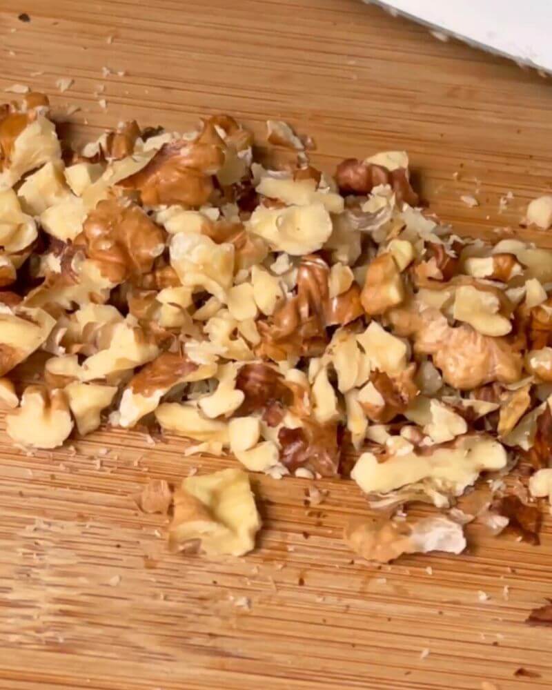 Chopped walnuts on a wooden chopping board.