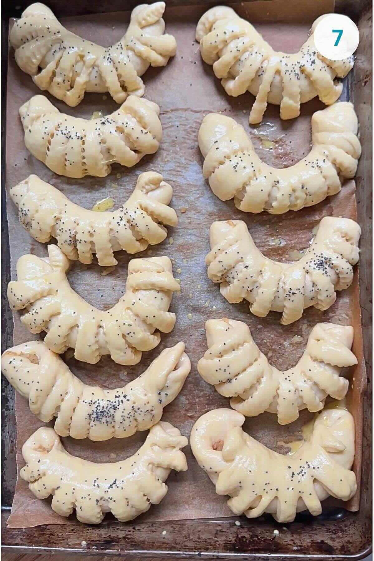 Risen rolls in a pan, brushed with egg wash, ready to be baked.