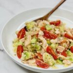 Flaky salmon mixed with fluffy couscous and fresh herbs in a bowl.