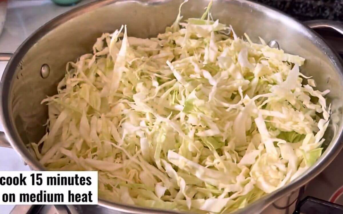 Finely chopped cabbage added in two batches to a pot with water, stirred and heated through.
