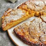 Close-up of a rustic apple cake slice, so full of tender apples that the batter is barely visible.