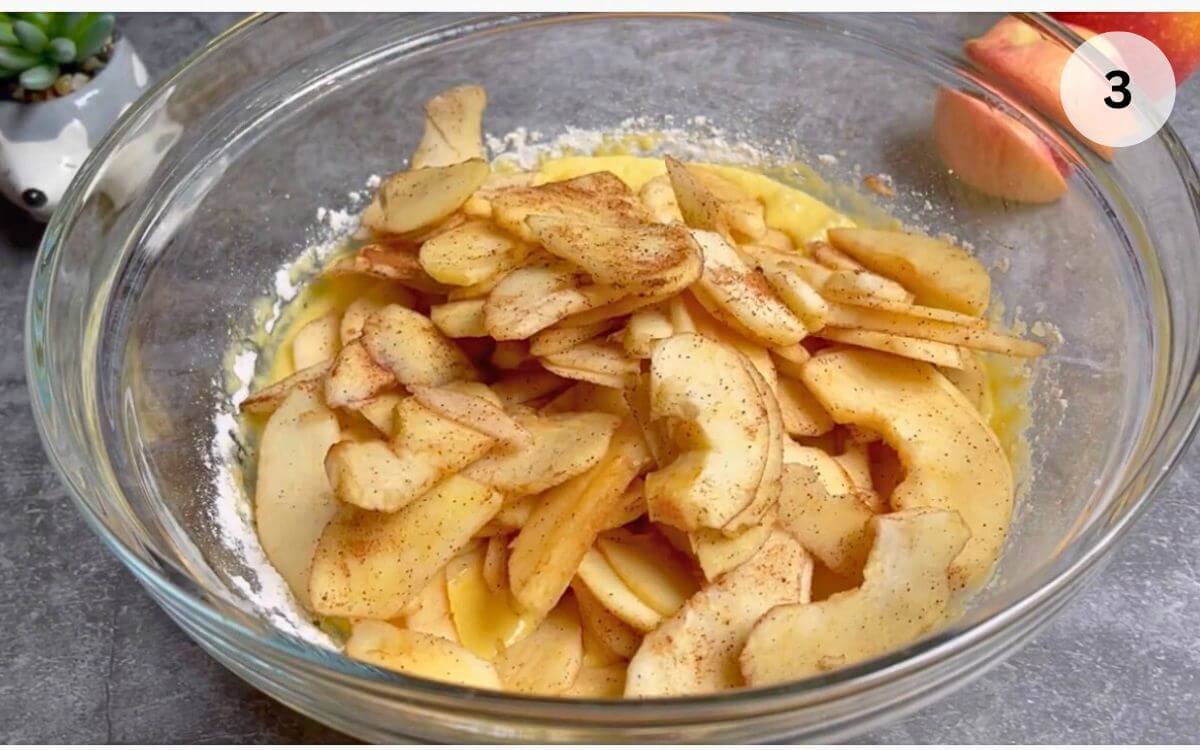 Cinnamon-coated apple slices added to the batter, ready to be folded in.