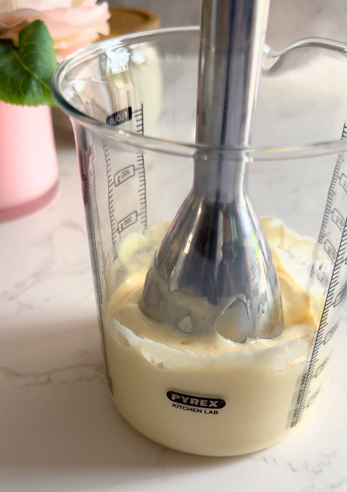 Immersion blender emulsifying sunflower oil, egg, mustard, lemon juice, and salt into creamy mayo in a glass jar.