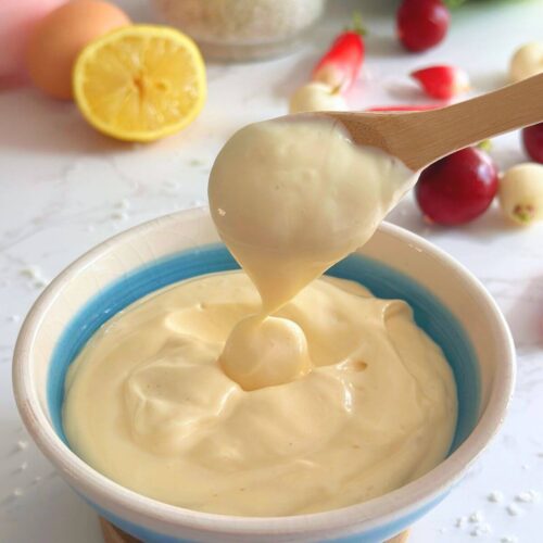 Homemade 4-ingredient mayo in a bowl, scooped with a wooden spoon to show creamy texture.