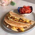 Two tacos with beef, crispy potatoes, Sriracha mayo, and green onions, served with tomato onion salad.