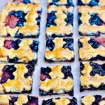 Homemade Italian cherry crostata cut into perfect squares, showing buttery crust layers.