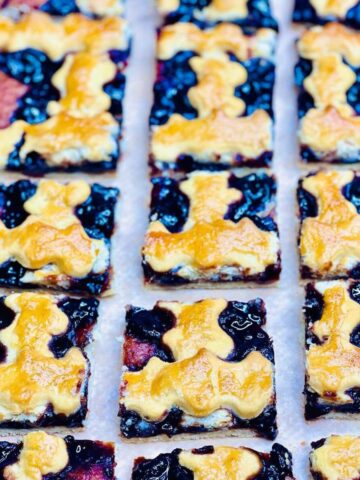Homemade Italian cherry crostata cut into perfect squares, showing buttery crust layers.